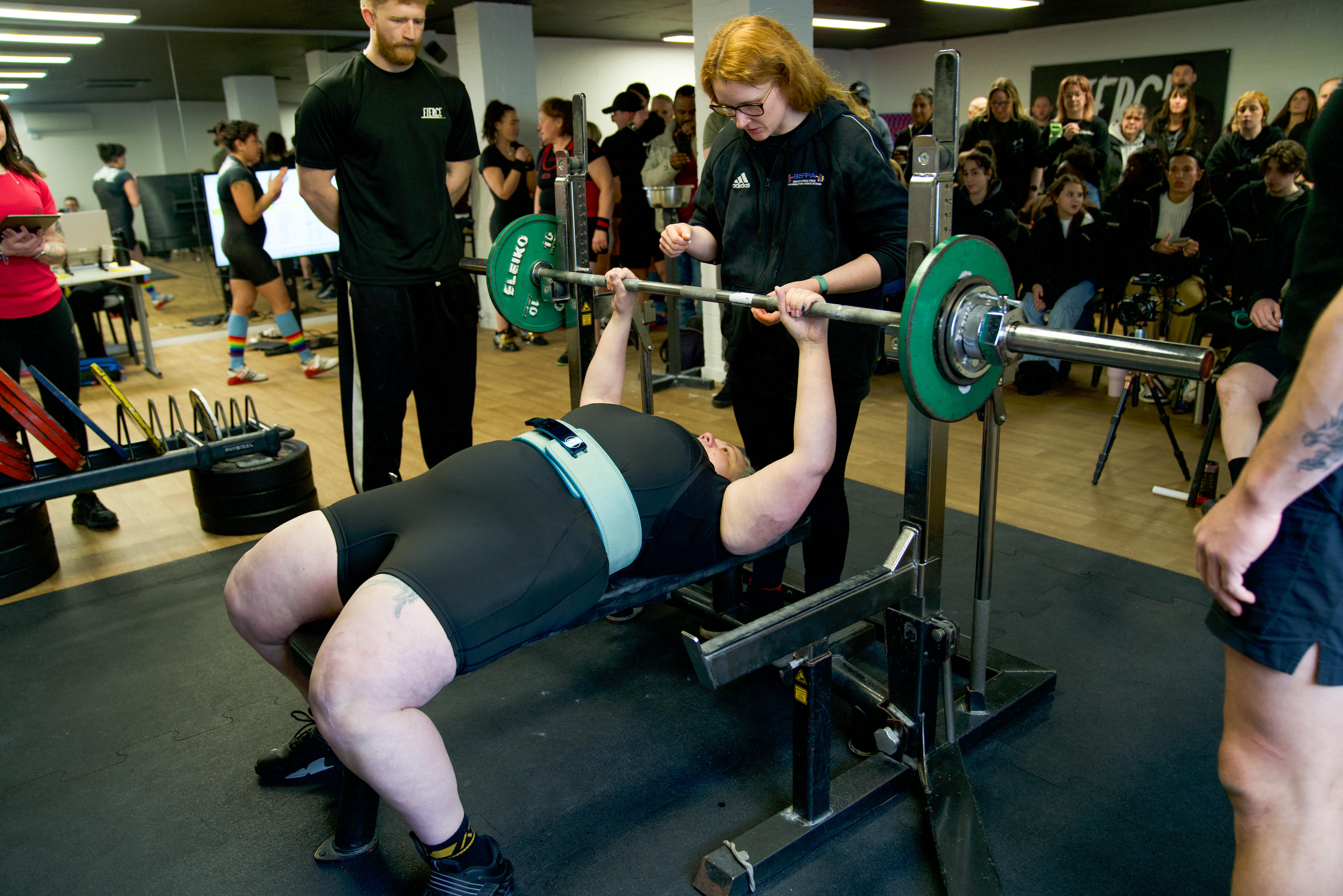 powerlifting coach handling national level bench presser during local competition