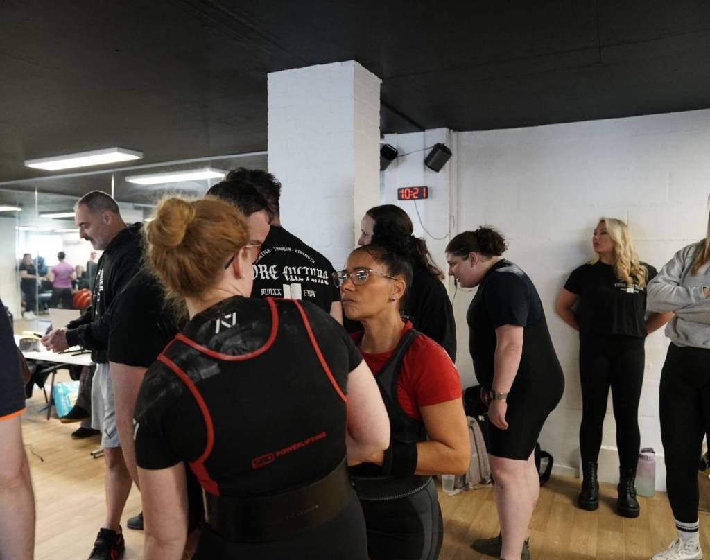 powerlifting coach assisting athlete with attempt selection at local competition